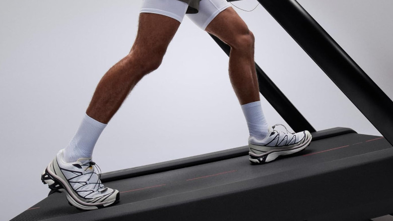 Человек, идущий по Peloton Tread+, установленному на крутом склоне.