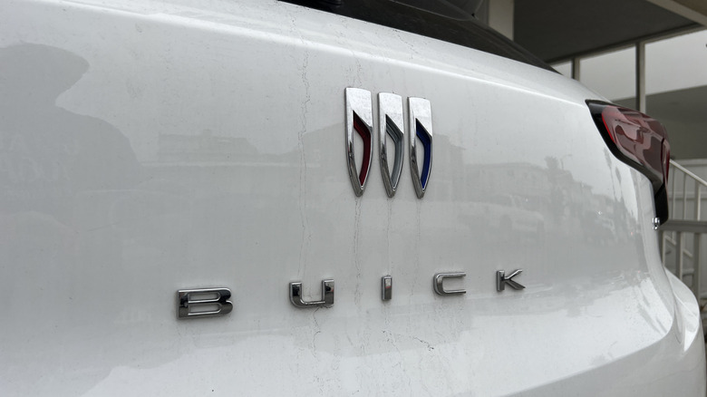 Крупный план логотипа Buick на кузове белого автомобиля.