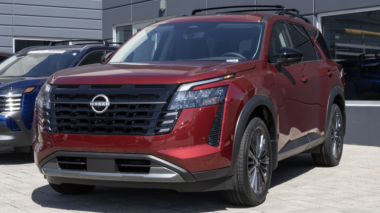 Красный Nissan Pathfinder припаркован перед автосалоном Nissan.