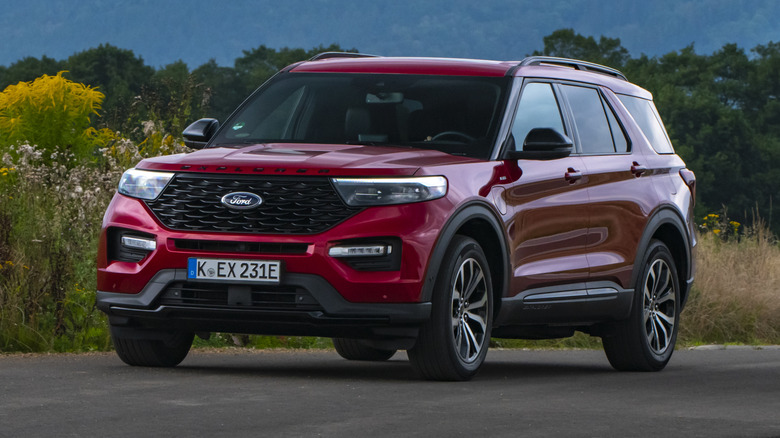 Красный гибрид Ford Explorer 2020 года едет по зеленой сельской местности.