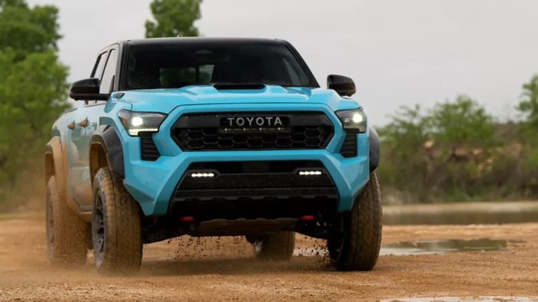 Синяя Toyota Tacoma на грязной грунтовой дороге в стране