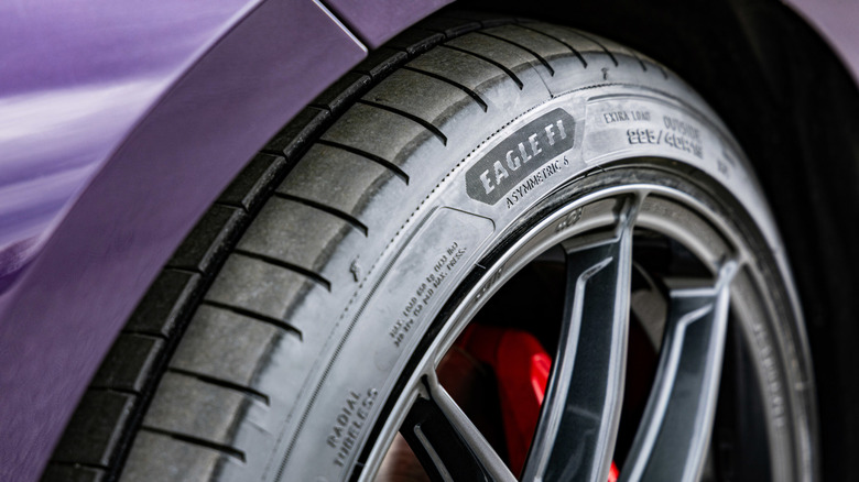 Крупный план боковины шины Goodyear Eagle F1 Asymmetric 6, установленной на колесе фиолетового автомобиля