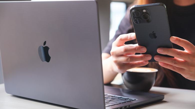 человек, использующий iPhone 15 и MacBook