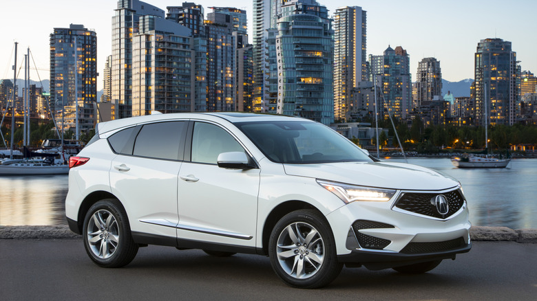 Белый Acura RDX 2019 года, припаркованный на фоне городского пейзажа.
