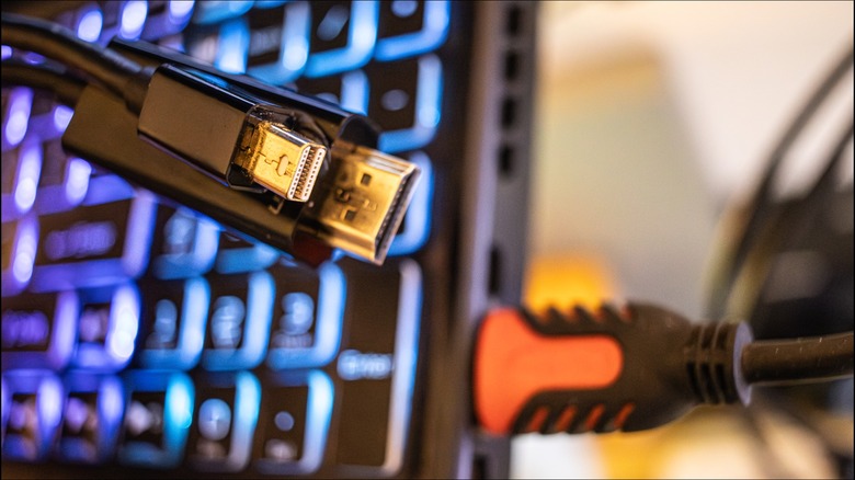 Кабель-адаптер mini-DP — HDMI перед ноутбуком с подключенным к нему кабелем HDMI.