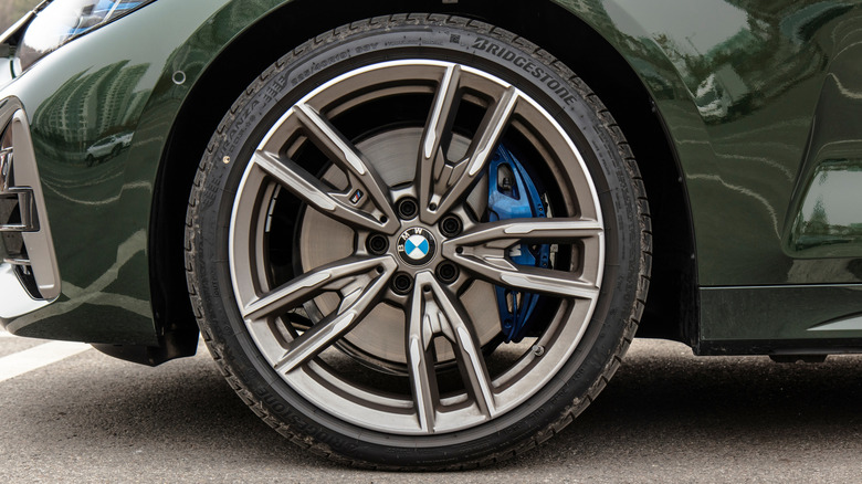 Крупный план темно-зеленого седана BMW с шинами Bridgestone.
