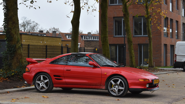 Toyota MR2 второго поколения SW20 припаркована возле кирпичного здания.
