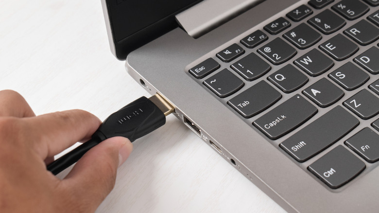 Человек, подключающий кабель HDMI к ноутбуку