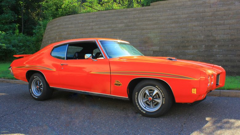 Оранжевый Pontiac GTO Judge 1970 года припаркован на дороге