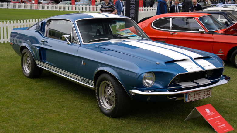 Сине-белый Shelby GT500 KR 1968 года, припаркованный на траве на автосалоне