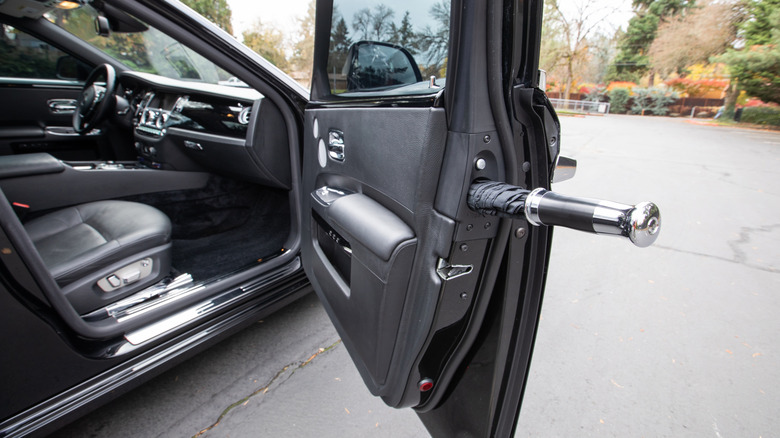Крупный план черного Rolls Royce Ghost с зонтиком в двери.