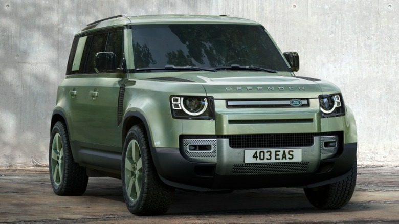 Зеленый Land Rover Defender 110 75-го ограниченного выпуска припаркован перед современным зданием