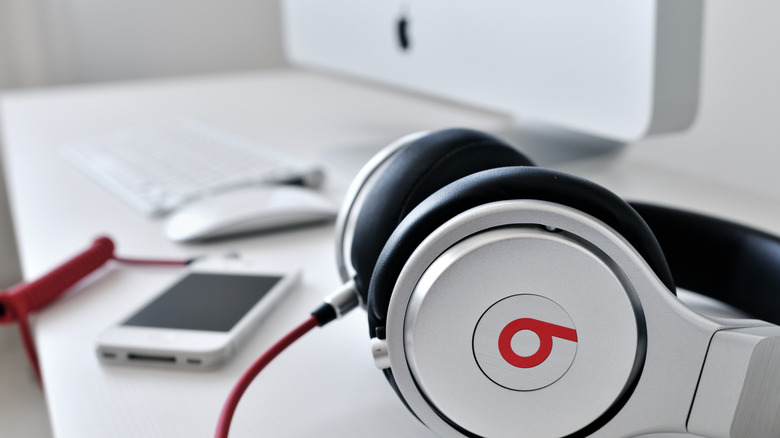Наушники Beats Audio лежат на столе рядом с iPhone и iMac.