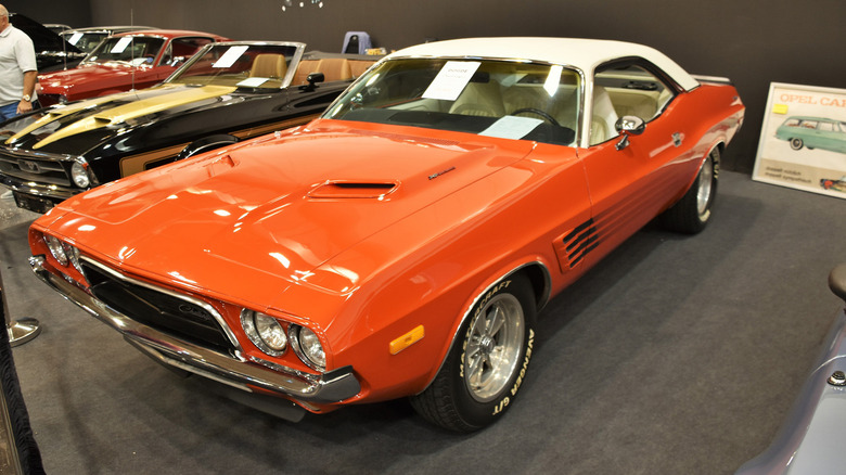 Ярко-оранжевый Dodge Challenger 1973 года выпуска в выставочном зале.