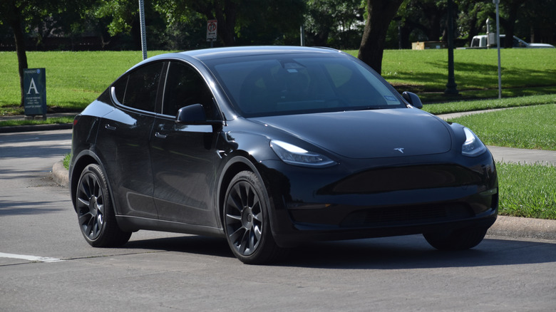 Затемненный внедорожник Tesla Model X EV ехал по дороге общего пользования.