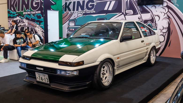 Вид спереди 3/4 белой Toyota Corolla AE86 на автосалоне.
