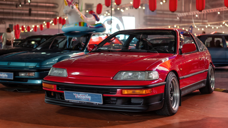 Вид спереди 3/4 на красную Honda CRX, припаркованную на автосалоне в помещении.