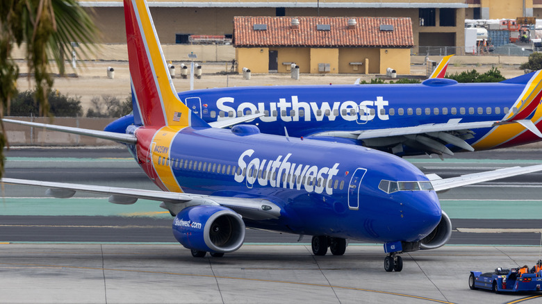Боинг 737-700 под брендом Southwest Airlines, вид спереди 3/4, на заднем плане еще один авиалайнер Southwest Airlines.