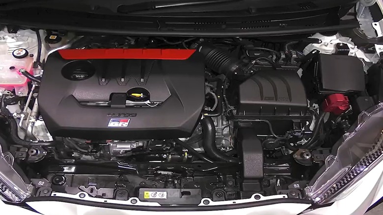 Двигатель Toyota G16E-GTS в фирменной красной крышке двигателя гордо сидит под капотом автомобиля, явно напоминающего мощный хот-хэтч.