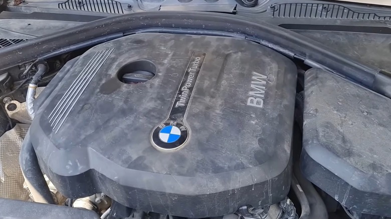 Пыльная крышка двигателя BMW B38 TwinPower Turbo под открытым капотом.