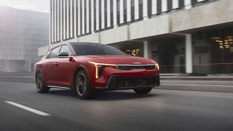 Красный Kia K4 2026 года выпуска едет по городской улице