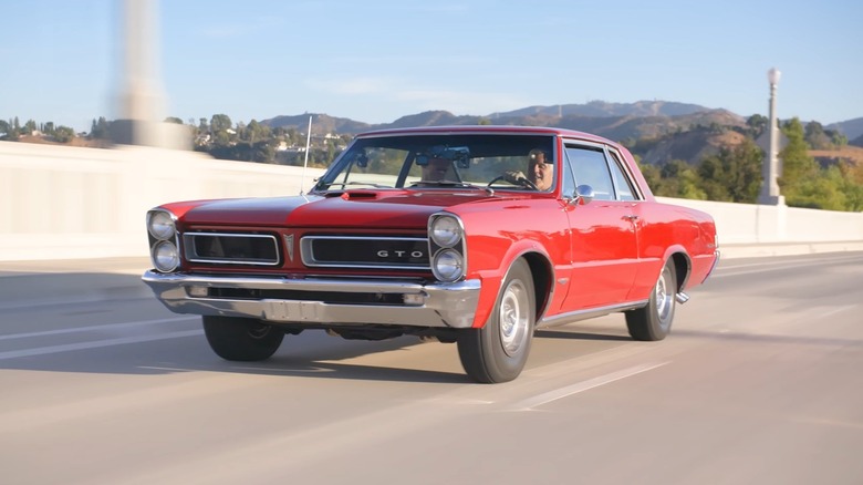 Джей Лено за рулем красного Pontiac GTO Royal Bobcat на шоссе