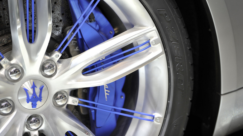 Синий трезубец Maserati в центре колеса серебристого автомобиля.