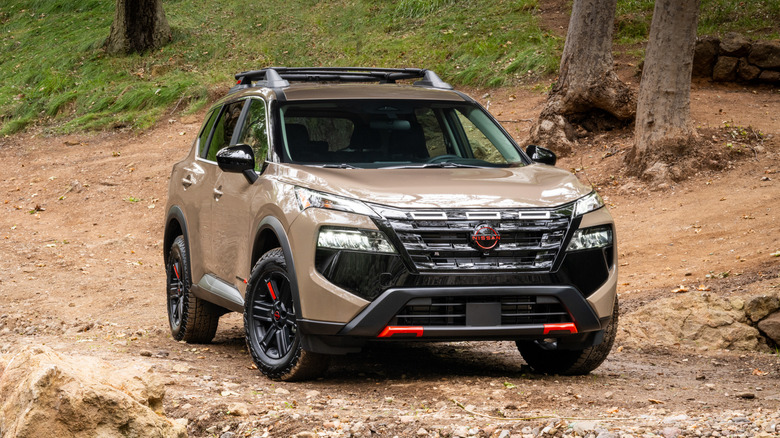 Светло-коричневый Nissan Rogue Rock Creek 2026 года выпуска, припаркованный на грунтовой дороге.