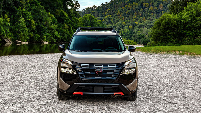 Вид спереди на Nissan Rogue Rock Creek 2026 года выпуска, припаркованный на гравийной дороге.