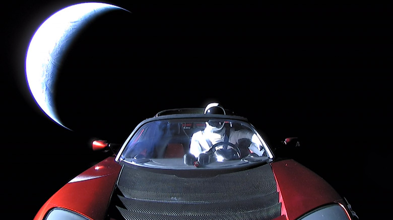 Красный родстер Tesla в космосе, за ним находится земля.