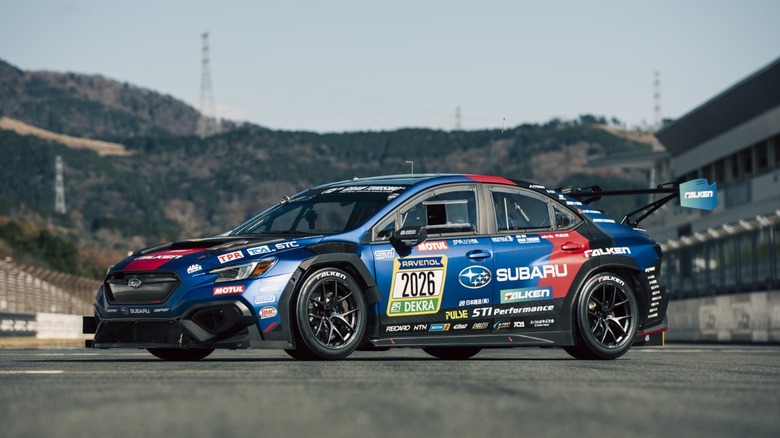 Вид спереди на 3/4 гоночного автомобиля Subaru WRX STI 2026 года, припаркованного на гоночной трассе.