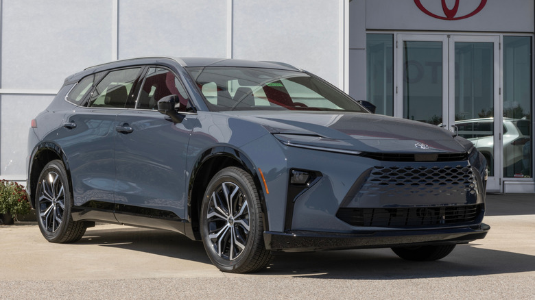 Вид спереди 3/4 серой Toyota Crown Signia, припаркованной у дилерского центра Toyota.