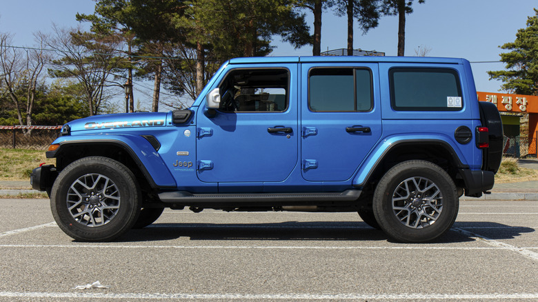 Вид сбоку на синий Jeep Wrangler 4xe, припаркованный на стоянке.