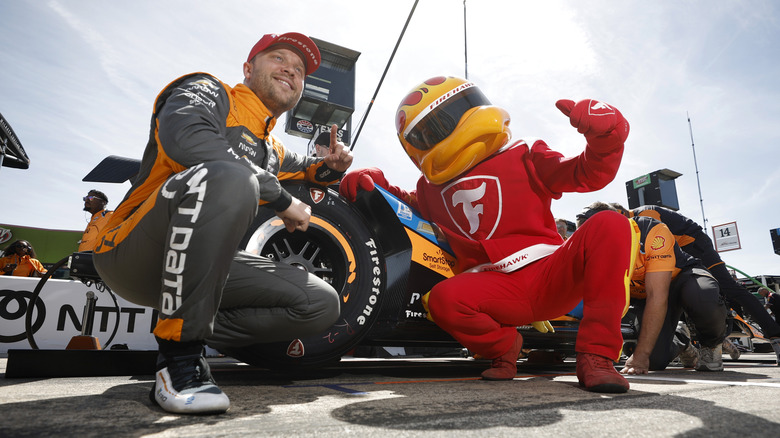 Низкий угол обзора талисмана Firestone Firehawk, позирующего для фото во время гонки в Инди.