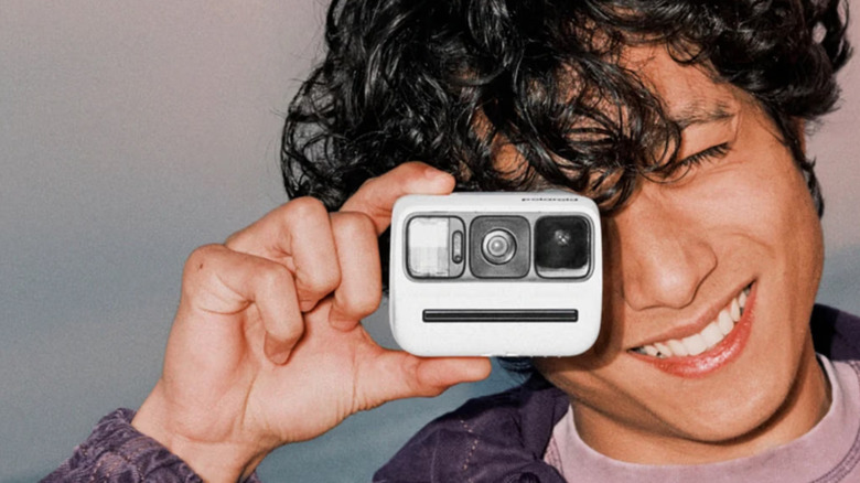 Человек, подносящий камеру Polaroid Go Instant Camera Generation 3 к правому глазу