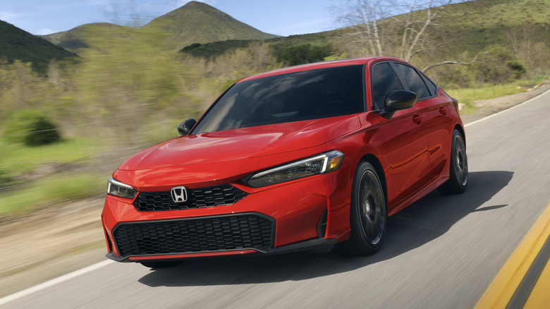 Вид спереди 3/4 на красный гибридный седан Honda Civic на горной дороге.