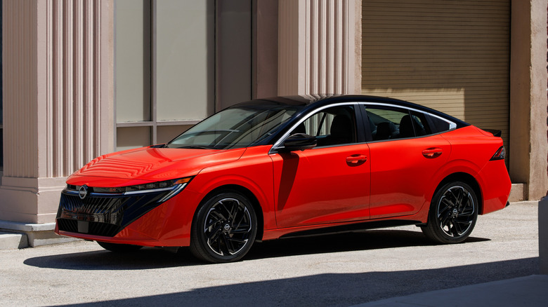 Вид спереди на 3/4 оранжевого Nissan Sentra 2026 года выпуска, припаркованного в переулке.