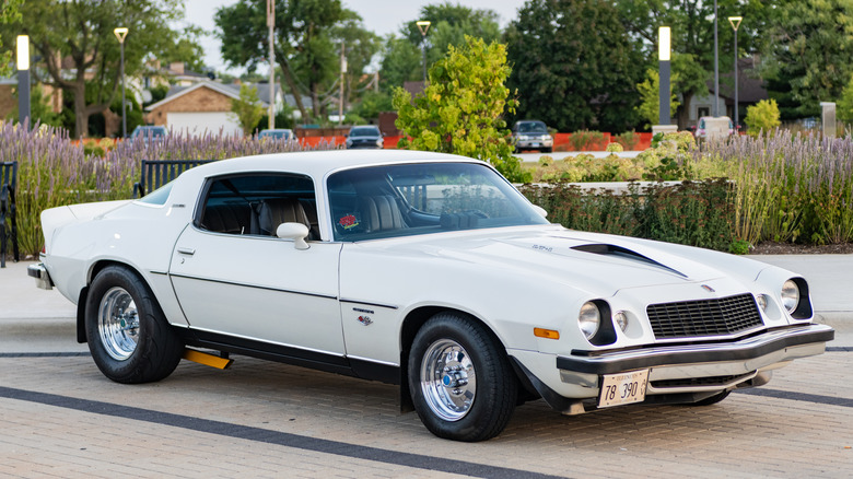 Вид спереди на 3/4 белого модифицированного Chevy Camaro 1970-х годов.