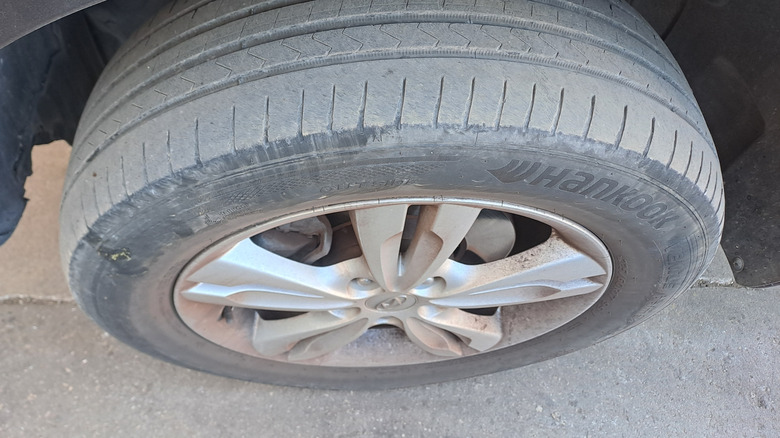 Вид сверху на грязную автомобильную шину с изношенным протектором.