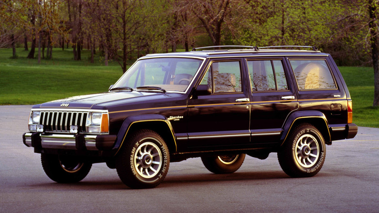 Jeep Cherokee XJ 1985 года, припаркованный на стоянке перед лесом, вид спереди слева в 3/4