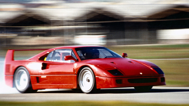 Ferrari F40 едет на скорости по гоночной трассе, вид спереди справа в 3/4