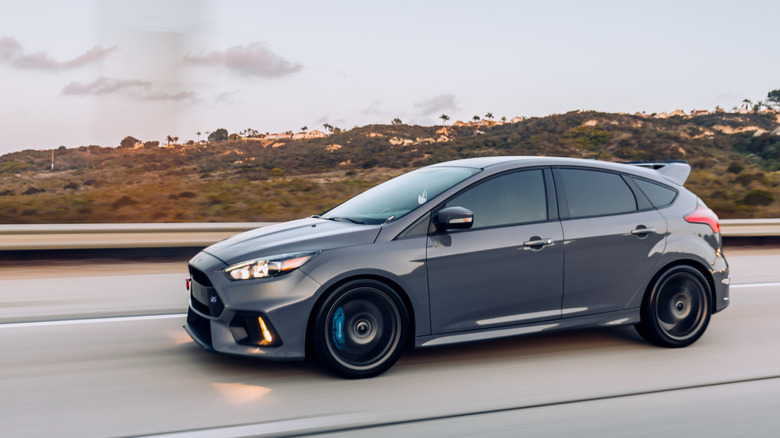 Вид сбоку на серый Ford Focus RS, едущий по шоссе.