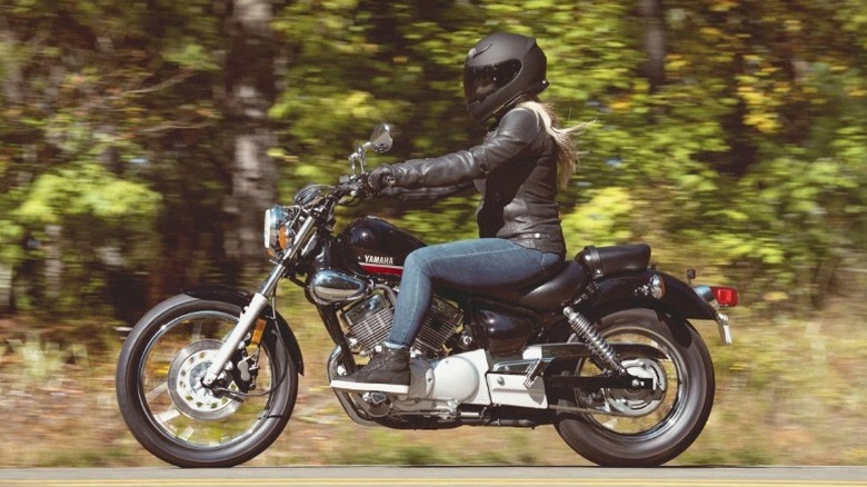 Человек едет на Yamaha V Star 250 по лесному шоссе
