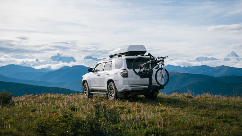 Белый Toyota 4Runner с багажником на крыше с видом на горы.
