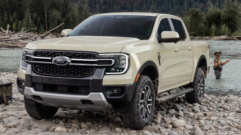 Бежевый Ford Ranger 2026 года выпуска, припаркованный на каменистом берегу реки.