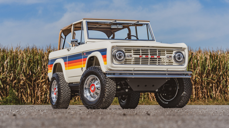Рестомод Ford Bronco первого поколения припаркован перед кукурузным полем.
