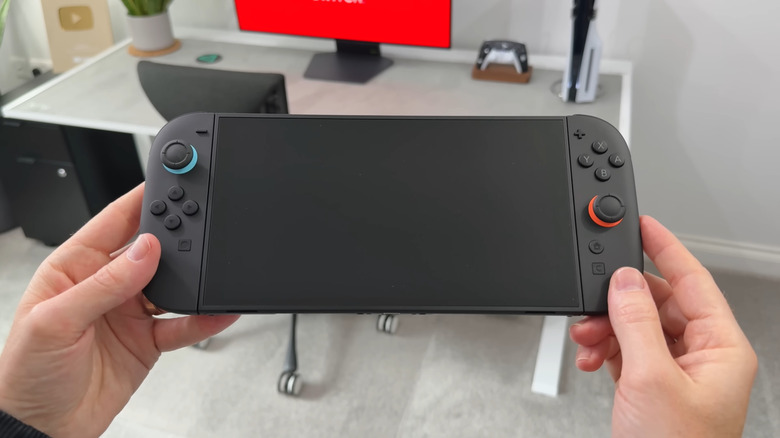 Человек с Nintendo Switch 2, экран выключен.