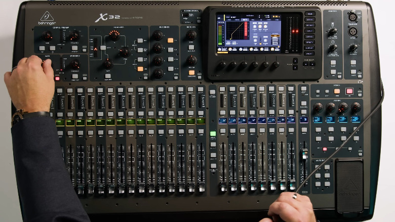 Человек, использующий невероятно большой полноразмерный Behringer X32.