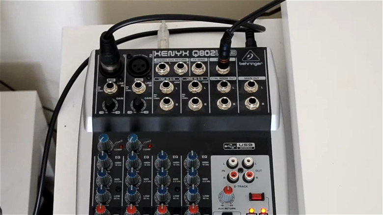USB-микшер Behringer Xenyx 802 на столе со вставленными кабелями.