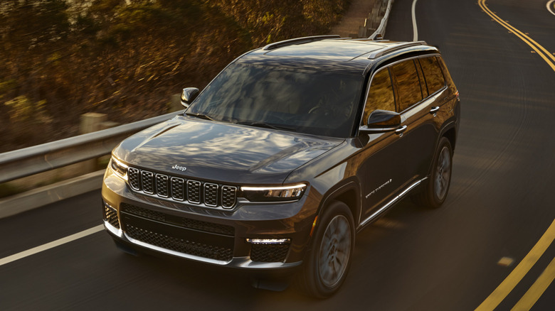 Вид спереди на 3/4 Jeep Grand Cherokee L на извилистой дороге в лесистой местности